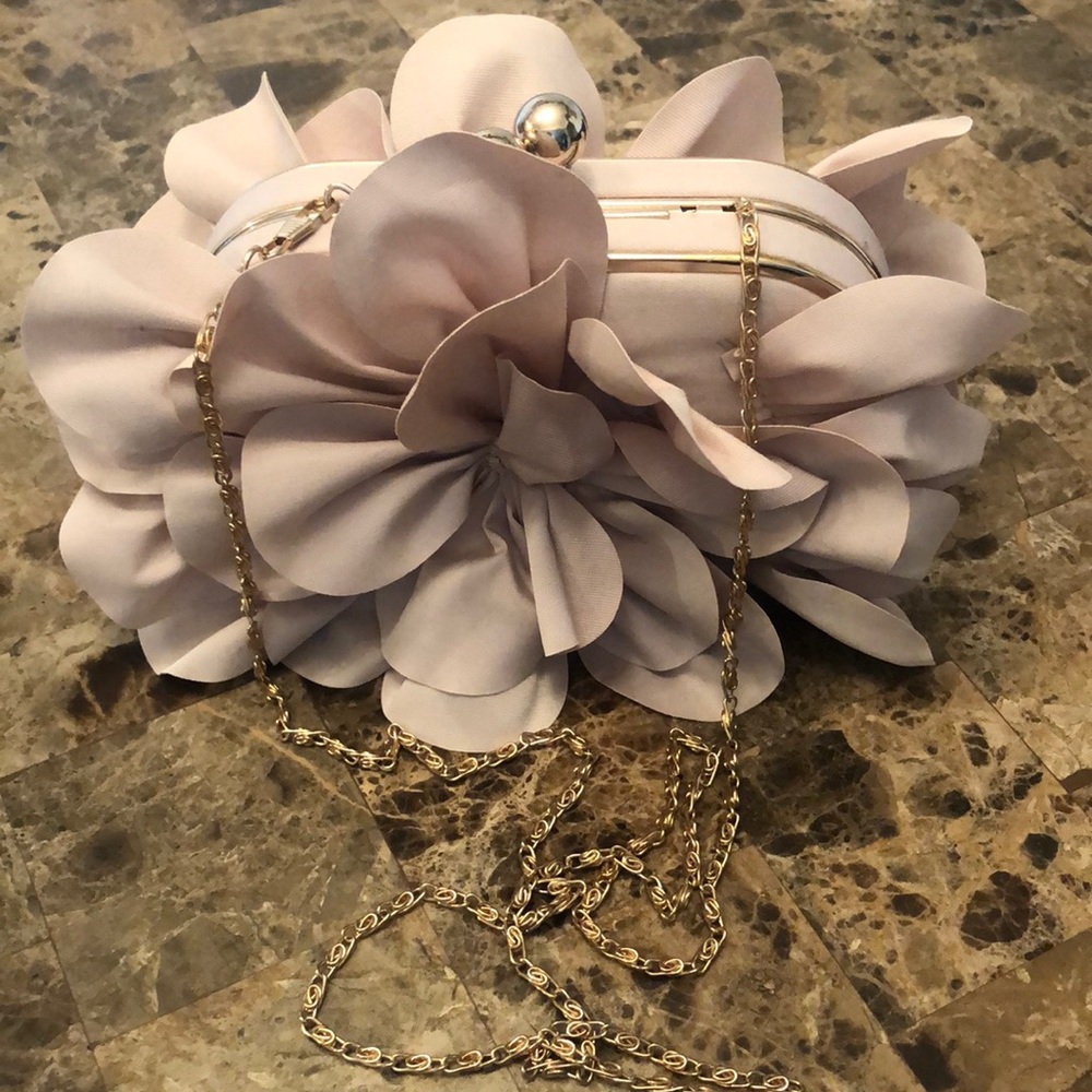 Clutch purse embellished with dusty rose flowers with a snap closure.